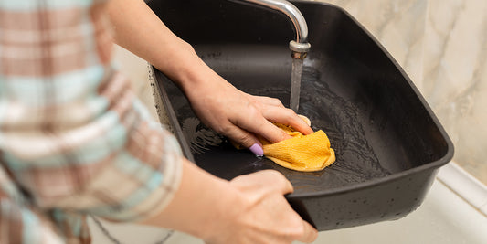 Cat-owner cleaning a soiled area with enzymatic cleaner to remove urine odor.